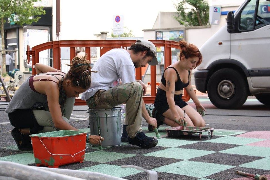 Artistes en action, peignant un motif à damier vert et noir dans une rue de Montreuil.